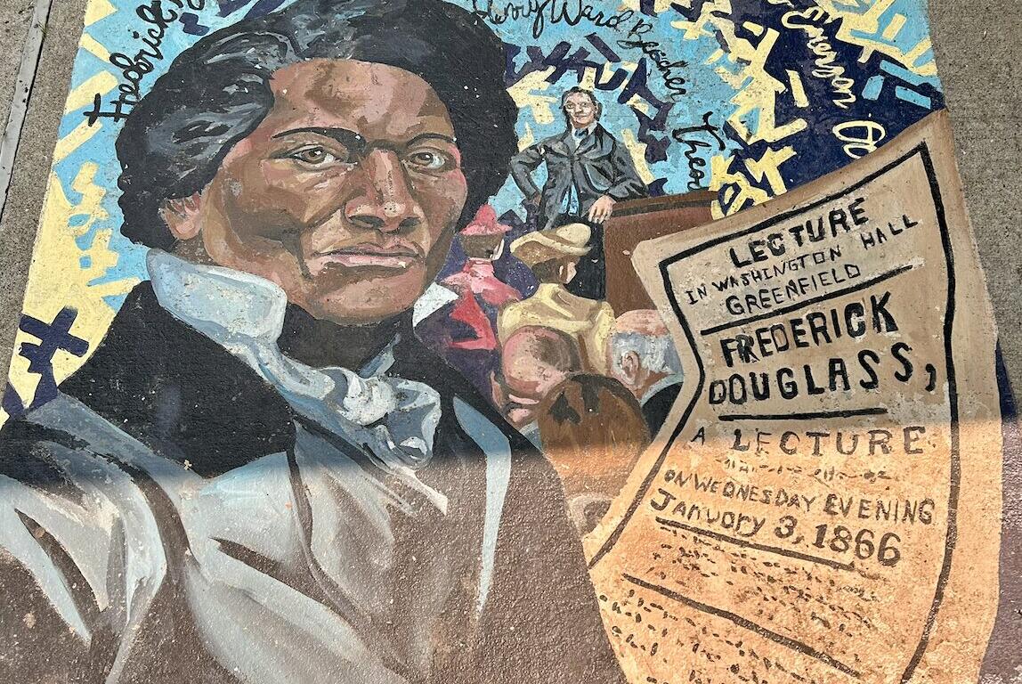 Colorful sidewalk mural featuring a close-up portrait of Frederick Douglass with a lecture poster and a crowd in the background.