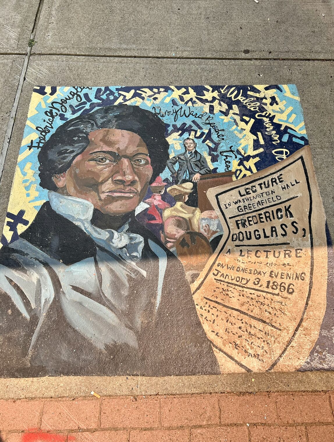Colorful sidewalk mural featuring a close-up portrait of Frederick Douglass with a lecture poster and a crowd in the background.