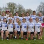 Group of players in white 'Four Rivers Ultimate' shirts posing together on a grassy field outdoors, smiling at the camera.