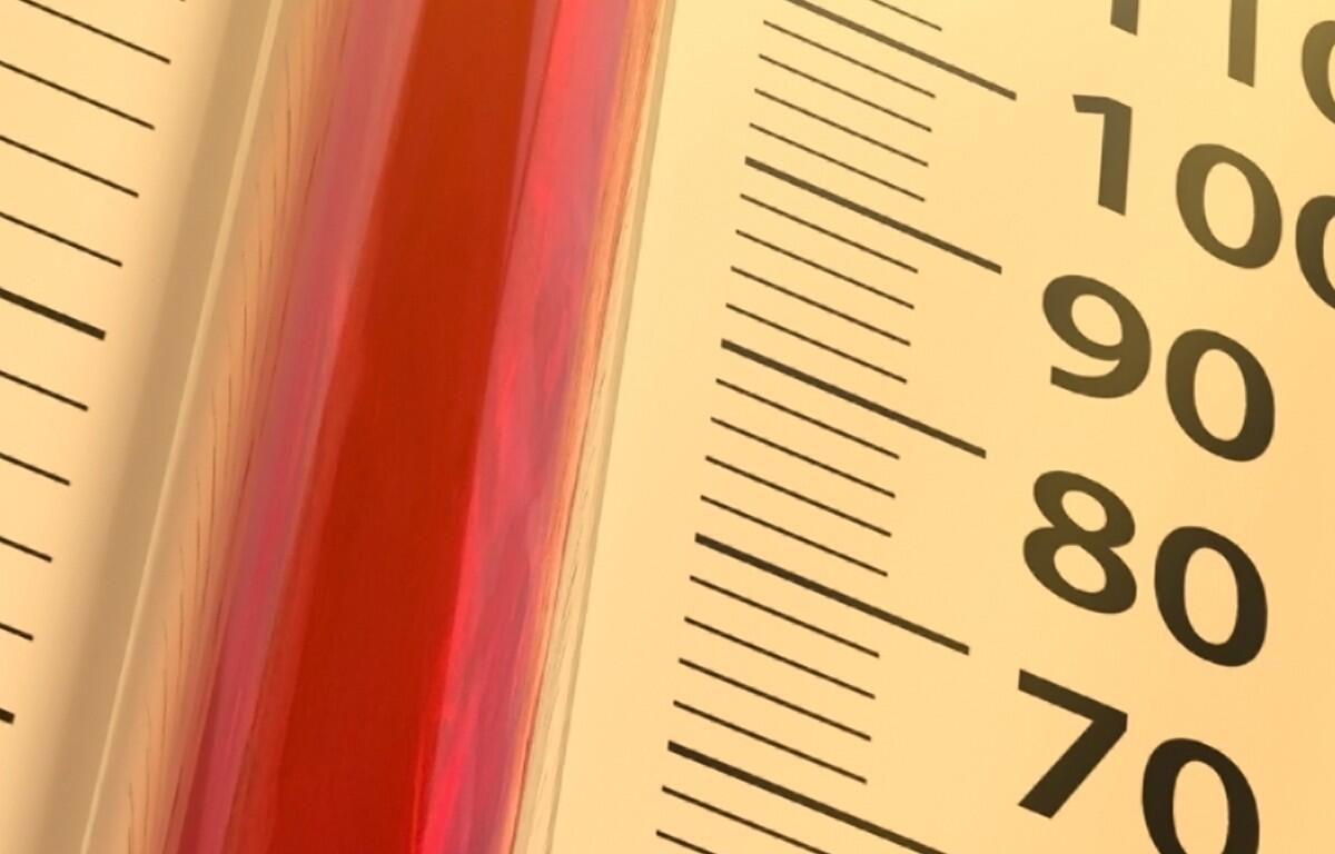 Close-up of a thermometer with red liquid against a yellow panel, showing scale marks and numbers 70–100.