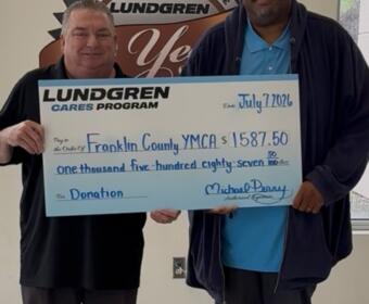 Two men indoors holding a large Lundgren Cares donation check made out to Franklin County YMCA for $1,587.50 dated July 7, 2020.