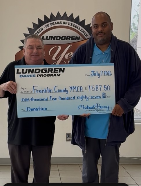 Two men indoors holding a large Lundgren Cares donation check made out to Franklin County YMCA for $1,587.50 dated July 7, 2020.